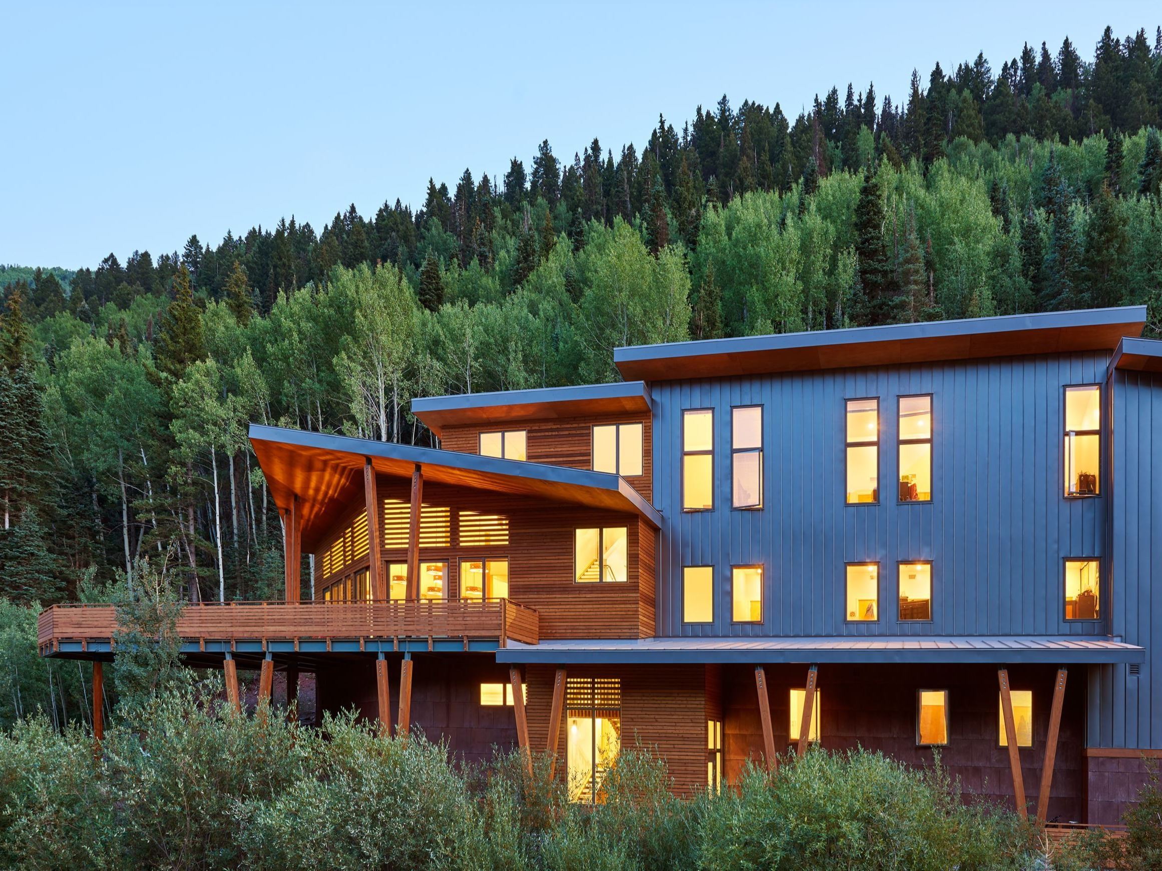The Boarding House lit up at night with wide windows and gray and wood exteriors. 